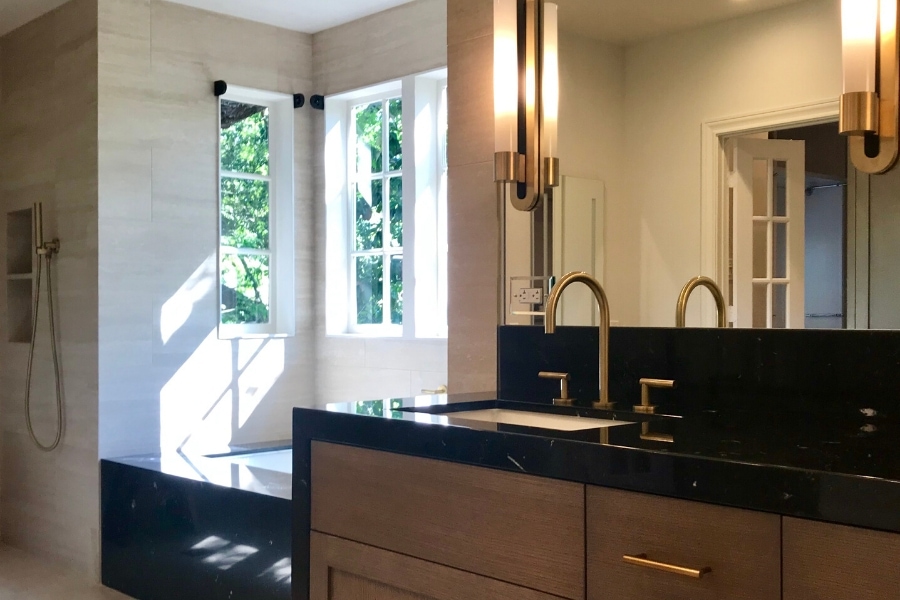 A bright and modern bathroom with mirror sconces and brushed brass fixtures
