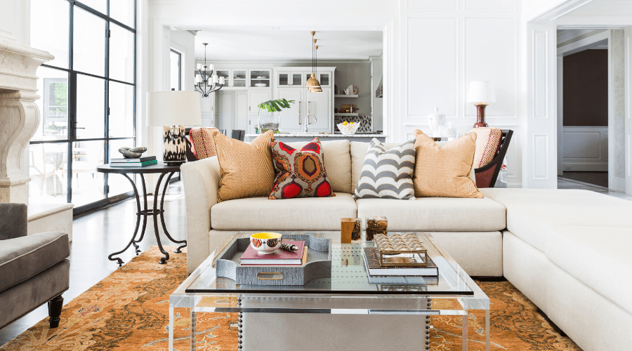 A cream sofa is paired with bold pillows and accompanied by a clear cocktail table.