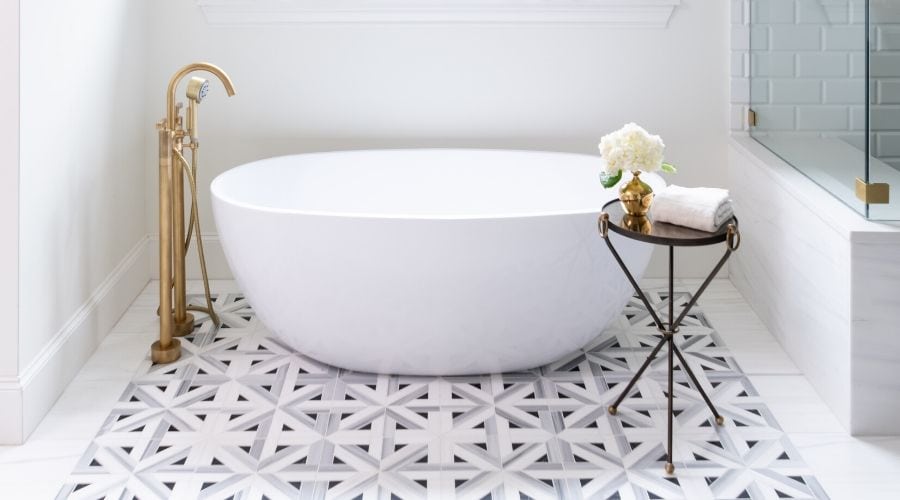 A soaking tub stands atop a black, gray, and white tile