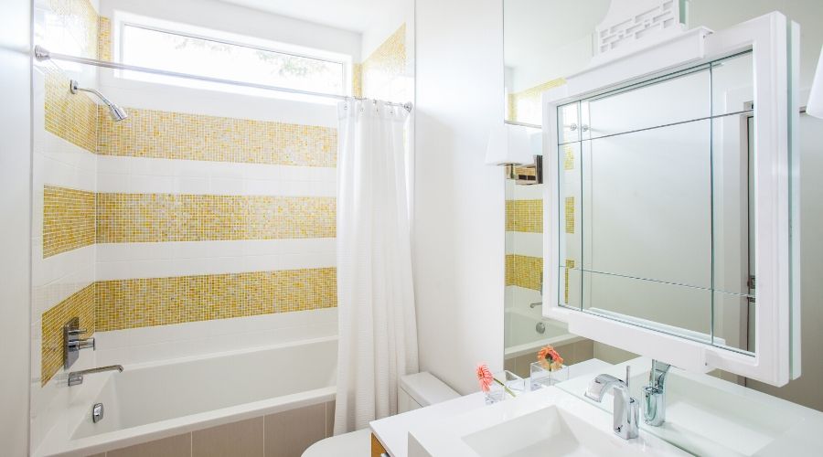 Bright pops of yellow tile bring sunshine to this full bathroom