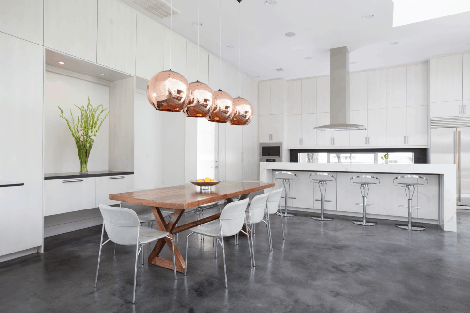 Copper pendant lights over a wooden table in an open concept kitchen and living room