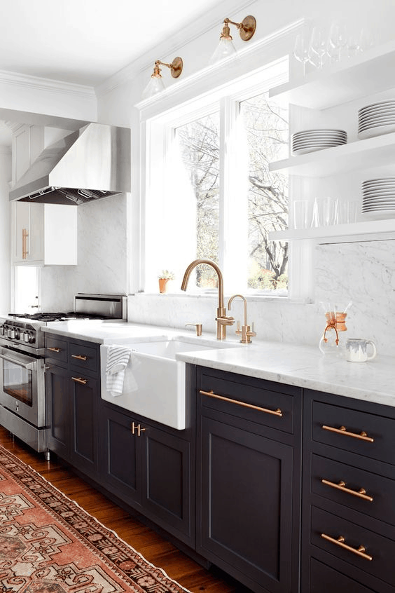 Kitchen with white marble backsplash and copper hardware on dark blue cabinets 