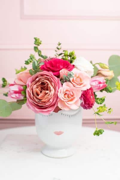 light and dark pink roses with greenery in white ceramic vase