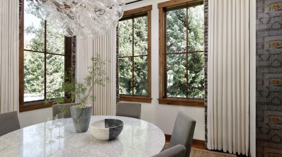 White drapery, gray furniture and a bubble candelier give this dining room a modern touch.