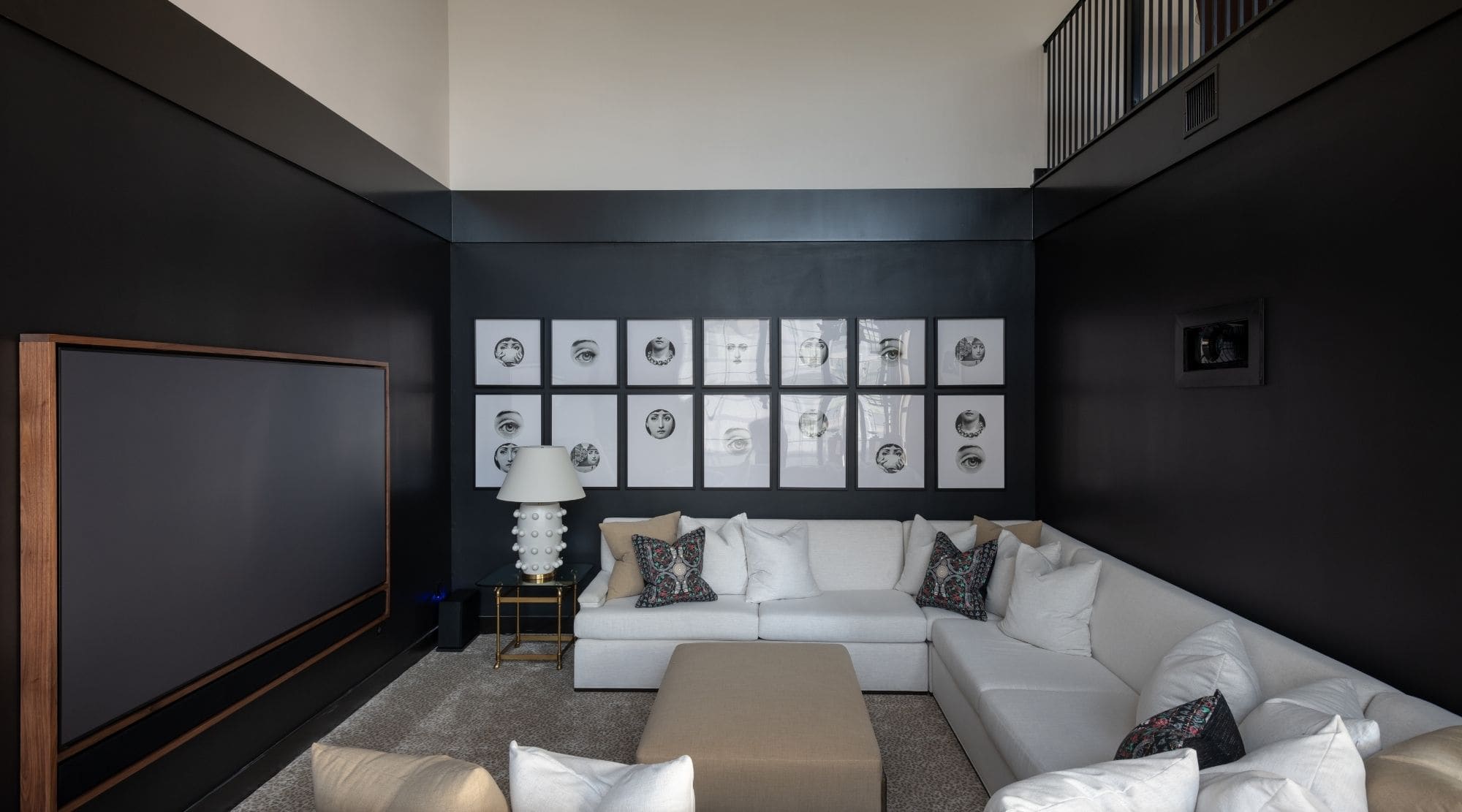 A high contrast media room with black walls and a white sectional sofa