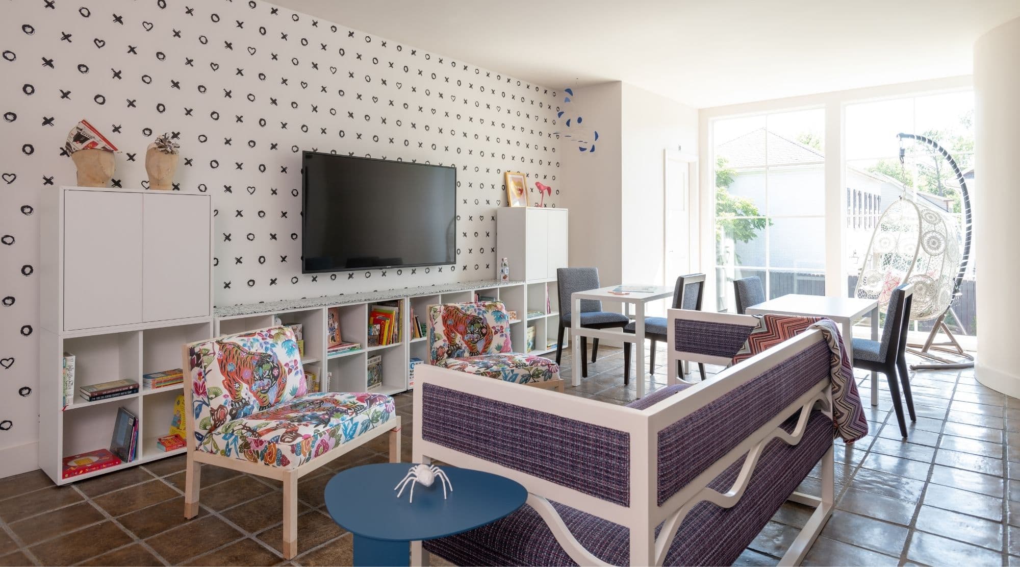 A colorful playroom with black and white wallpaper and lots of storage