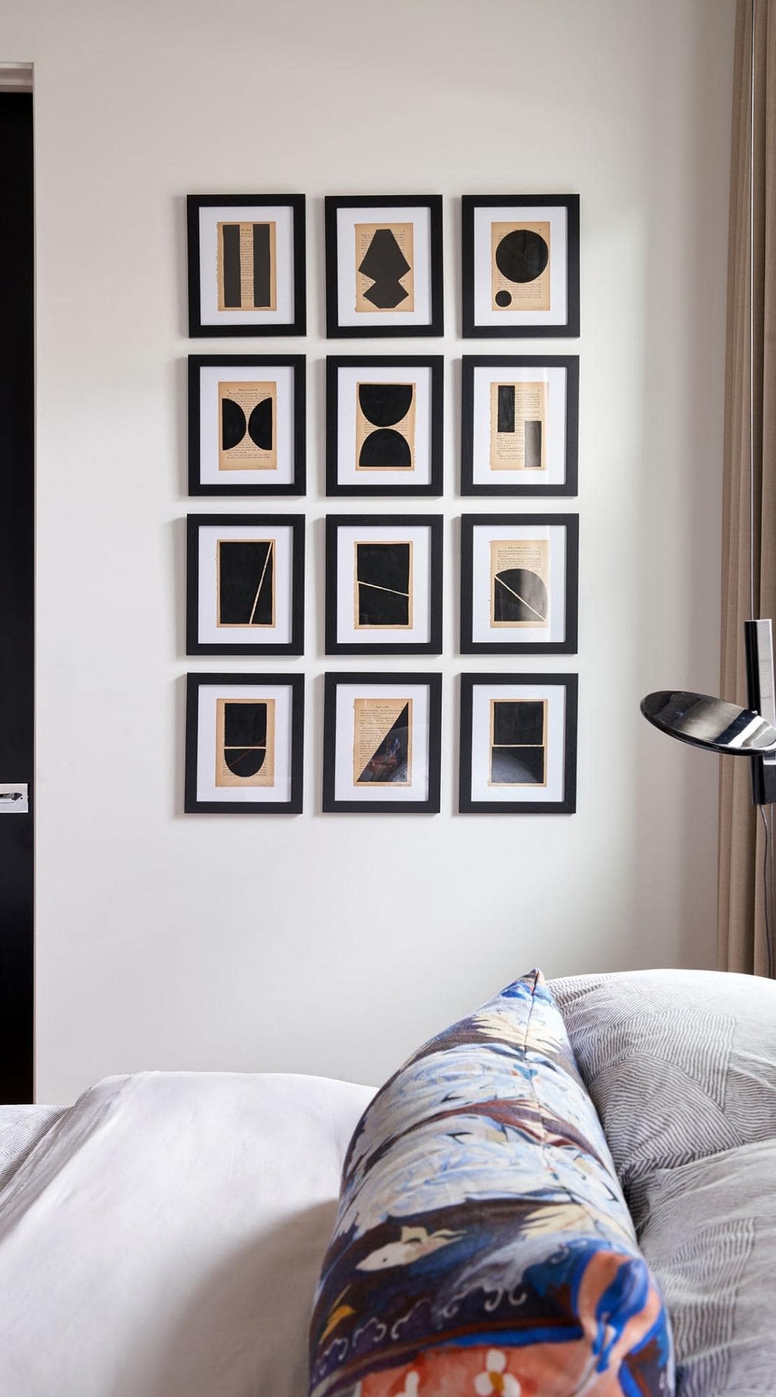 Contrasting white and black gallery wall with prints from Josh Young in the bedroom of a Houston home.