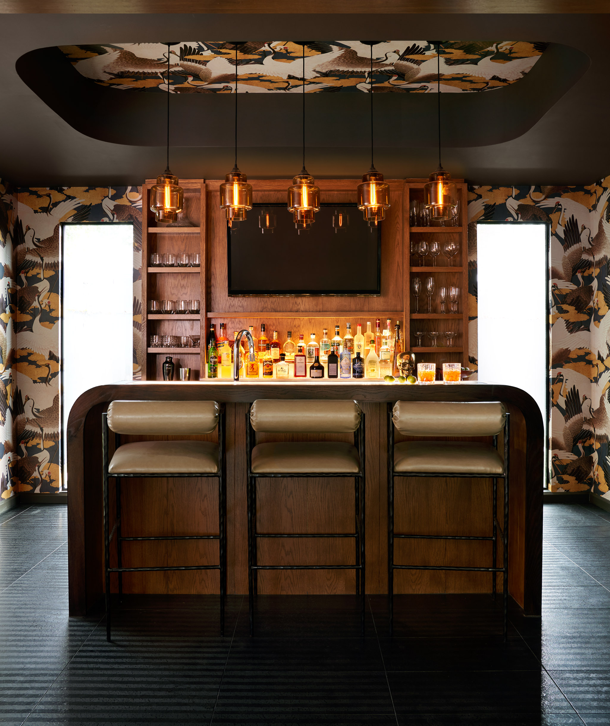 A sophisticated bar with ceiling wallpaper, designed by Laura U Design Collective