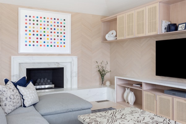 An artwork from Damien Hirst hangs in a modern family room, designed by Laura U.