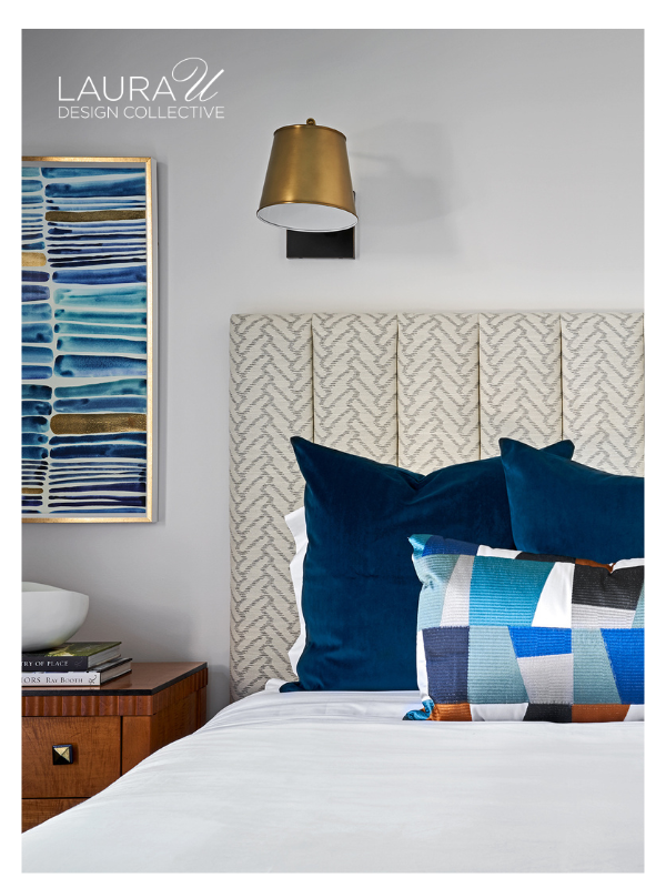 Cream upholstered headboard with white bedding, blue velvet accent pillows, and a geometric blue lumbar pillow.