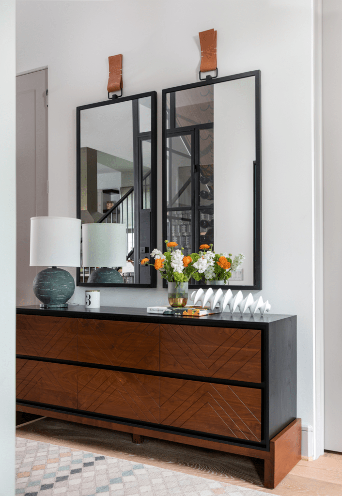 Bright Foyer with brown wooden platform chest and conrasting mirror in this Dunstan home 
