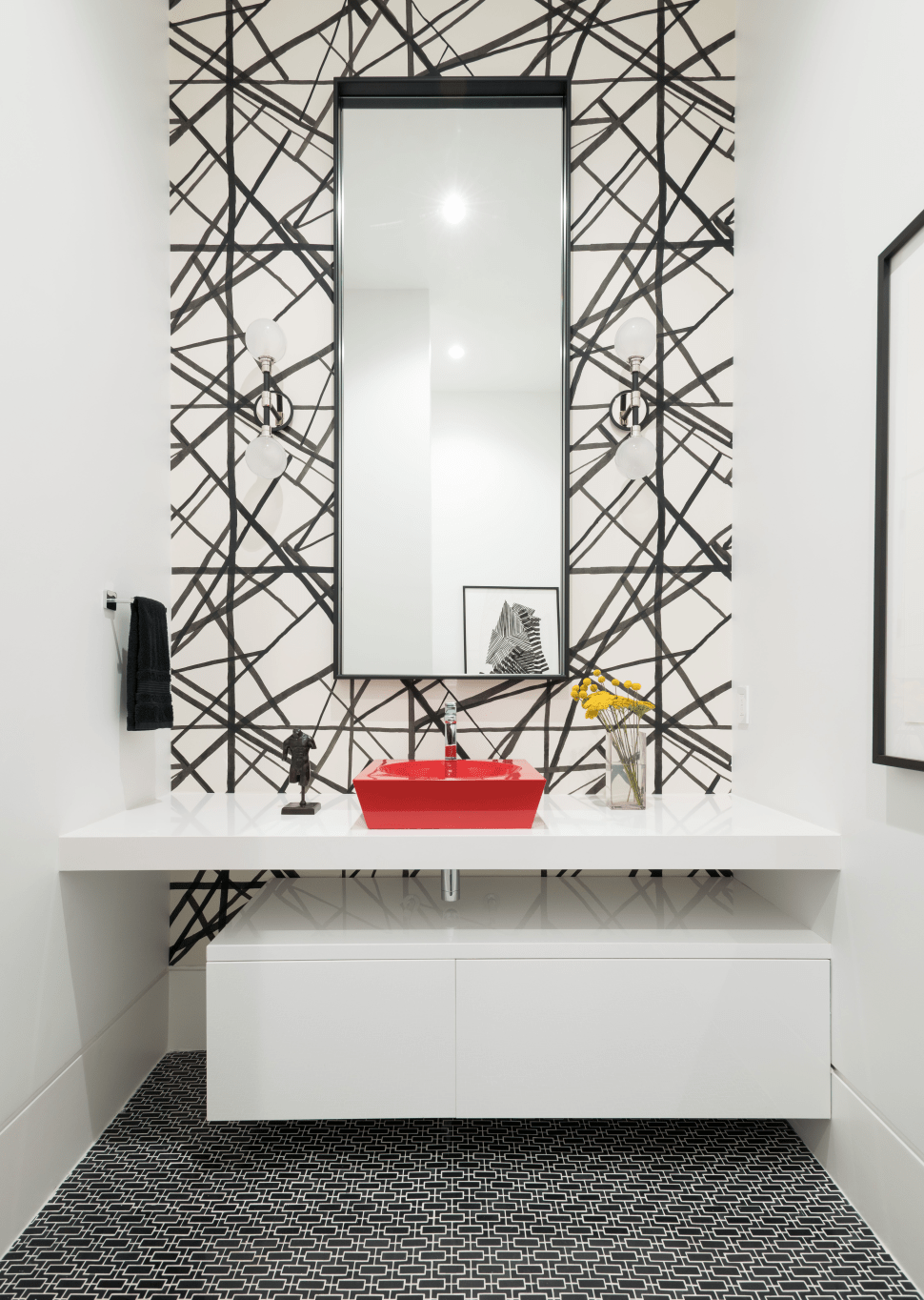 Dramatic powder room with black and white backsplash, red basin and high-gloss white cabinets.