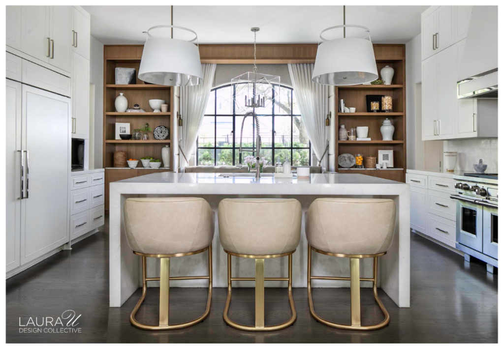 White kitchen with open wood shelving flanking a large arched window, a marble island, and three upholstered counter stools.