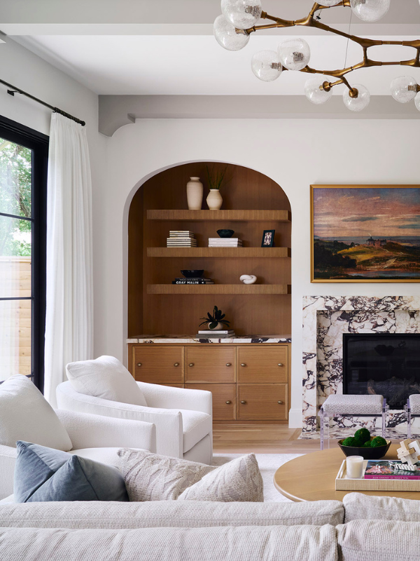 Living room with recessed arched built-in shelving flanking a marble fireplace and custom wood cabinetry.