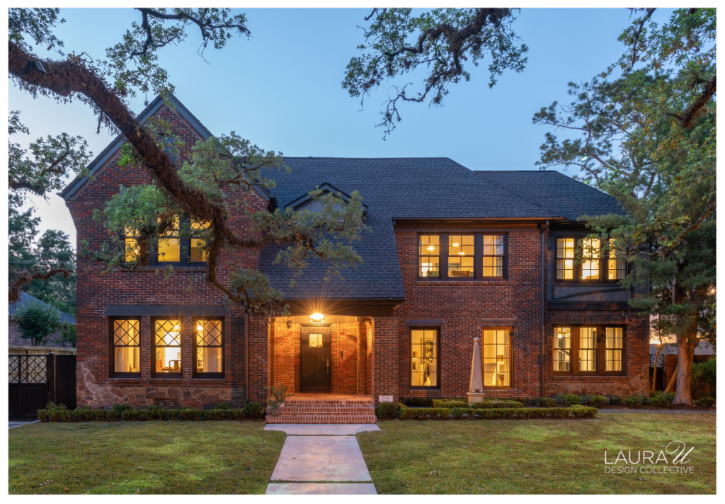 Brick Tudor Revival home photographed at dusk with warm interior light glowing through the windows.