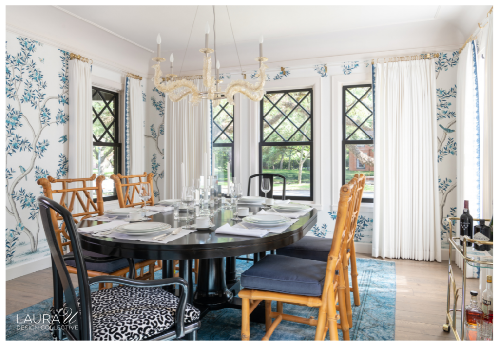 Dining room with hand-painted blue-and-white wallpaper, black-framed windows, white drapery, mixed dining chairs, and a glass chandelier.