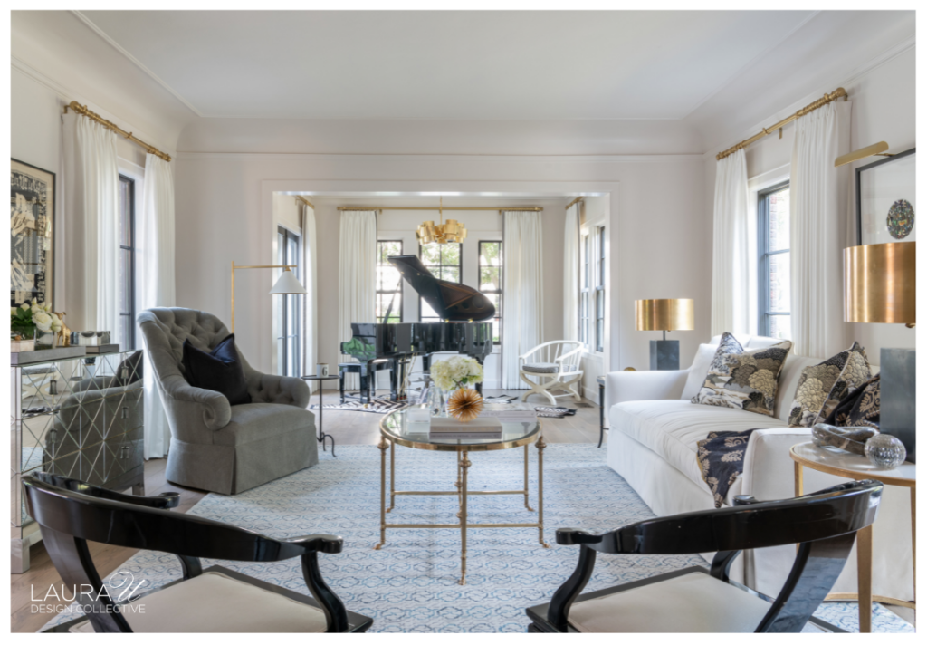 Bright formal living room with white drapery, brass lamps, mirrored cabinetry, neutral upholstery, and a grand piano beyond.