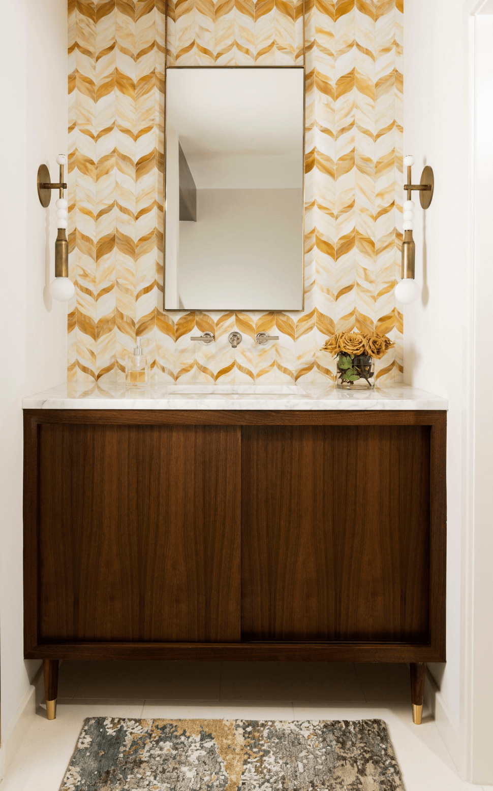 Powder room with brown wood cabinets, biege wall and brass lights 