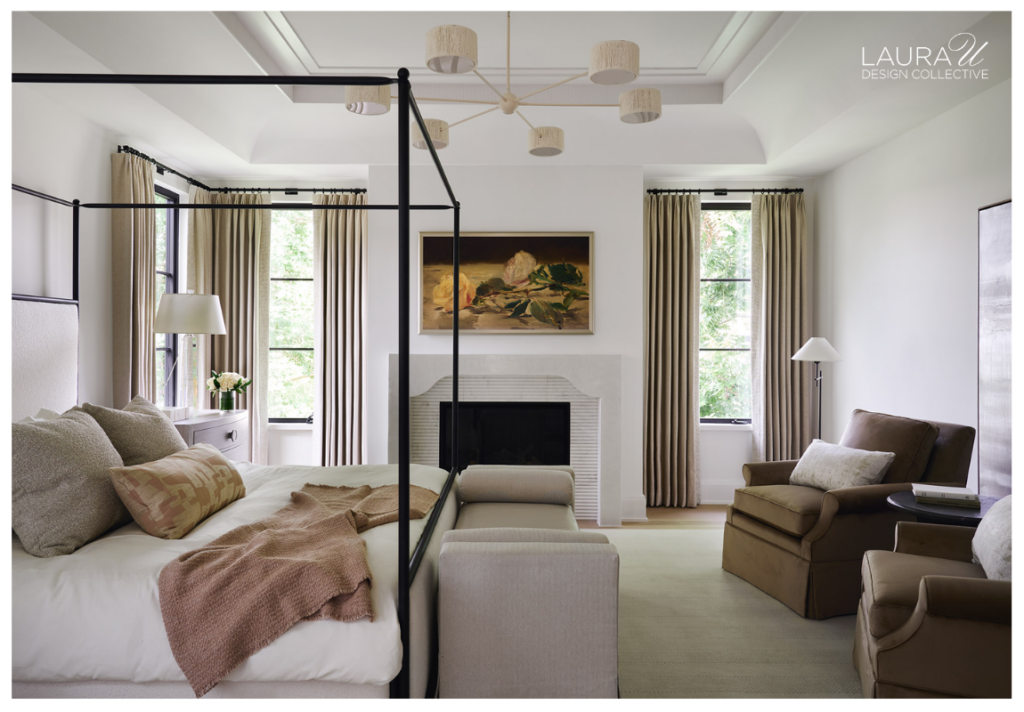 Neutral primary bedroom with an iron canopy bed, fireplace, floor-length drapery, upholstered seating, and soft layered finishes.