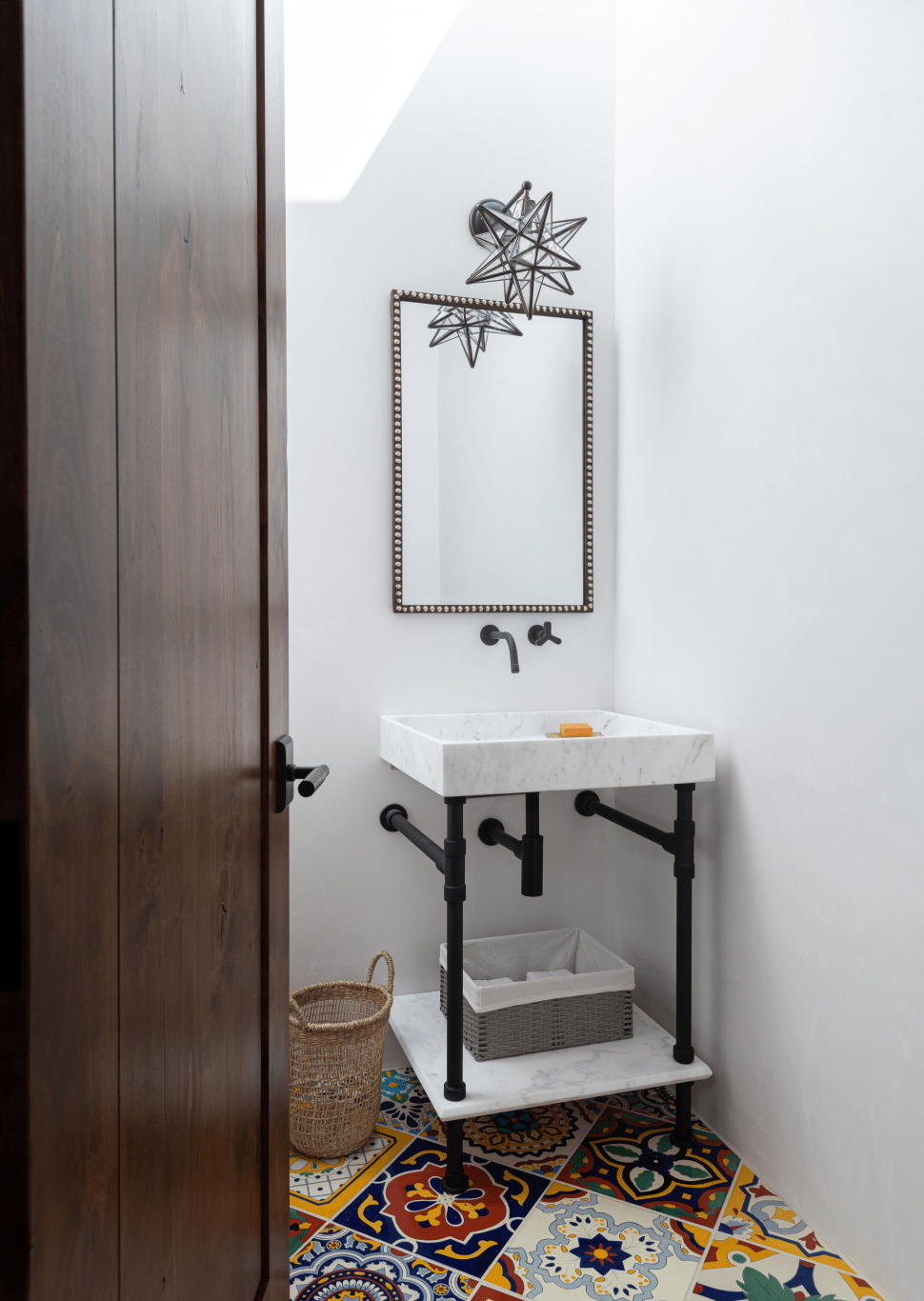 White walls, white & black sink contrasts with the colorful tile floor 